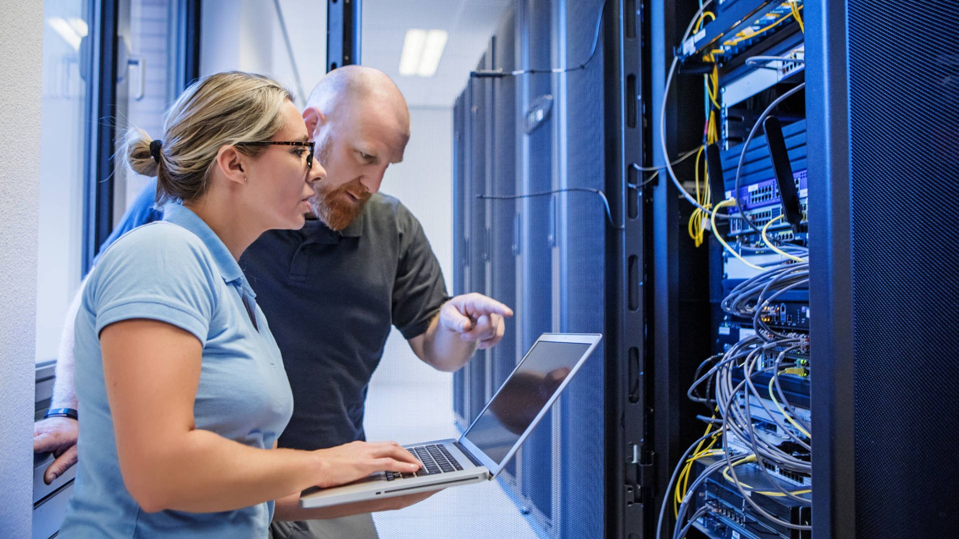 Zwei IT-Techniker (männlich und weiblich) arbeiten in einem Serverraum mit einem Laptop