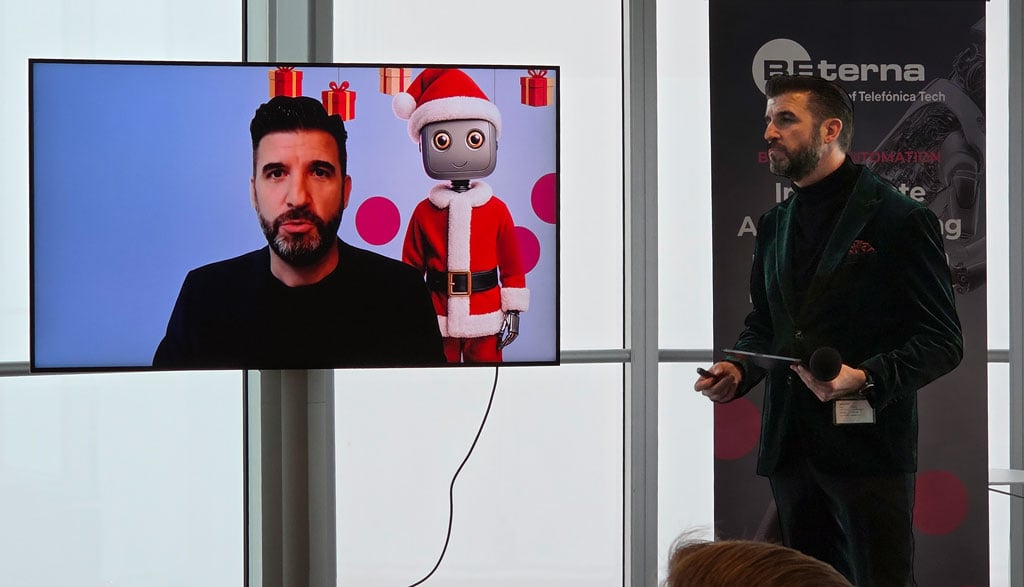 Vortrag beim BE-terna Event im o2 Tower: Chris Malloy präsentiert KI-Inhalte, während auf dem Bildschirm ein digitaler Avatar im weihnachtlichen Design zu sehen ist.