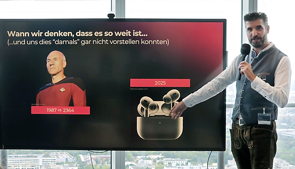 Chris Malloy von BE-terna zeigt beim o2 Business Event im o2 Tower München, wie schnell technologische Entwicklungen wie KI Realität werden – mit Beispiel aus Star Trek und Apple AirPods.
