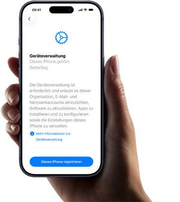Eine rechte Hand hält ein iPhone, dessen Display einen Text mit einer Beschreibung der Geräteverwaltung und der Option zum Anmelden zeigt
