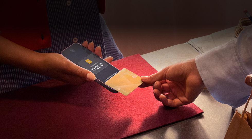 Eine Hand hält eine Kreditkarte an ein iPhone, um eine Transaktion abzuschließen