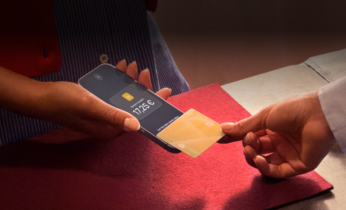 Eine Hand hält eine Kreditkarte an ein iPhone, um eine Transaktion abzuschließen