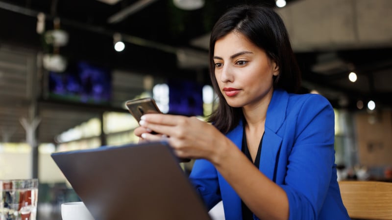 Moderne Geschäftsfrau mit Handy und Laptop bei der Arbeit