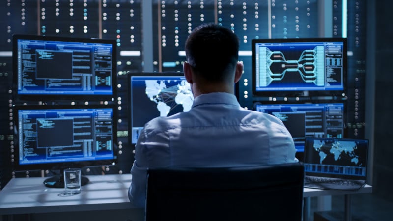 Data Loss Prevention (DLP): Ein IT-Techniker sitz vor mehreren Bildschirmen, auf denen Systeminformationen zu sehen sind.