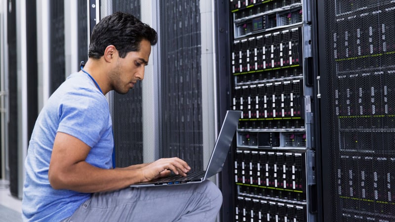 Ein IT-techniker mit einem Laptop überprüft die Sicherheit in einem Serverraum
