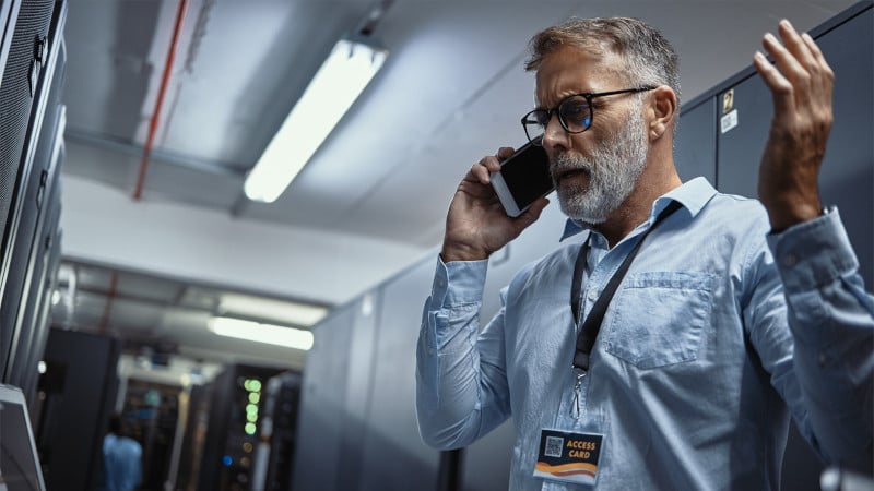 Ein Mitarbeiter telefoniert aufgebracht im Technikraum