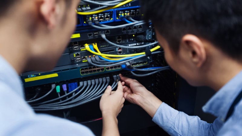 Zwei Mitarbeiter prüfen die Ethernet-Verbindung am Server-Schrank