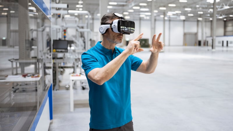 Ein Mann arbeitet mit VR-Brille in einer Fabrikhalle