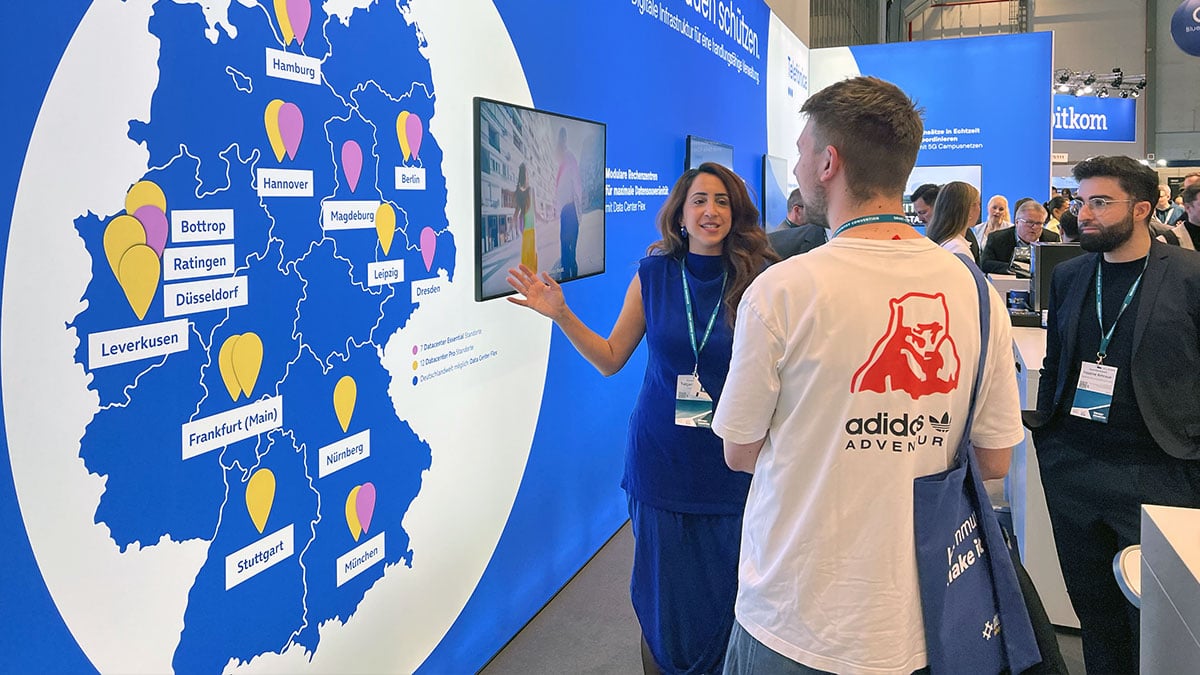 Beratungsgespräch vor der Deutschlandkarte mit den Rechenzentrumsstandorten am Messestand