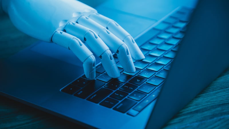 Eine Roboterhand tippt auf einem Laptop