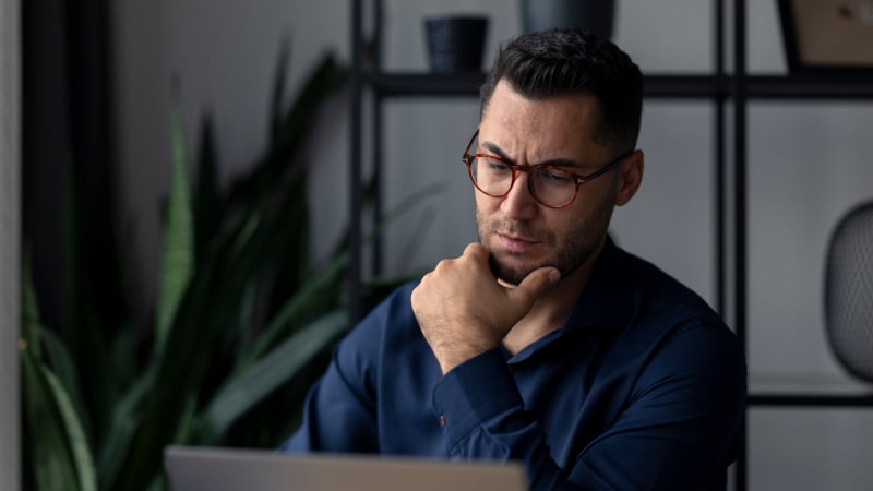 Nachdenklicher Geschäftsmann schaut auf Laptop