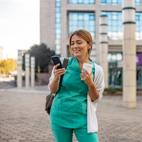 Eine weibliche Pflegefachkraft mit einem Smartphone unterwegs