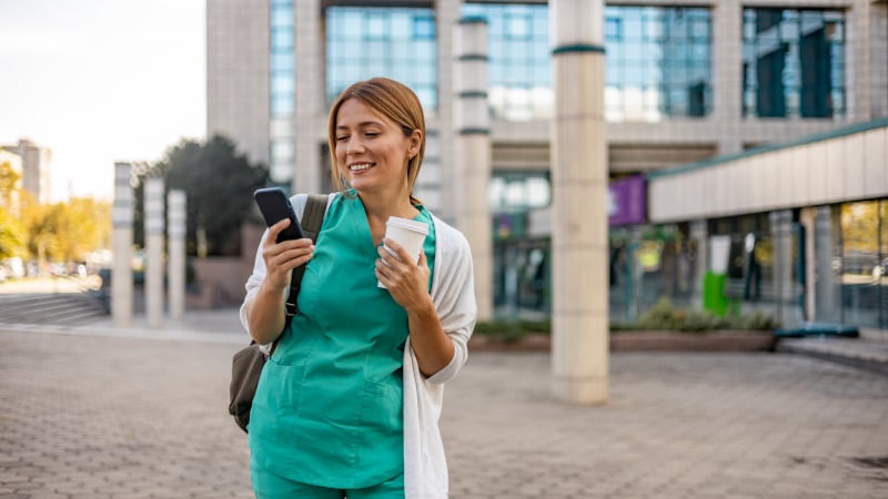 Eine weibliche Pflegefachkraft mit einem Smartphone unterwegs