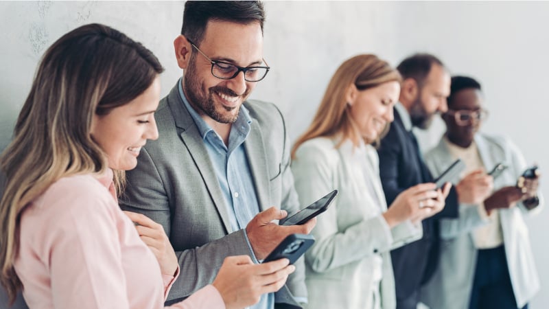 Mitarbeiterinnen und Mitarbeiter unterhalten sich und nutzen mobile Geräte