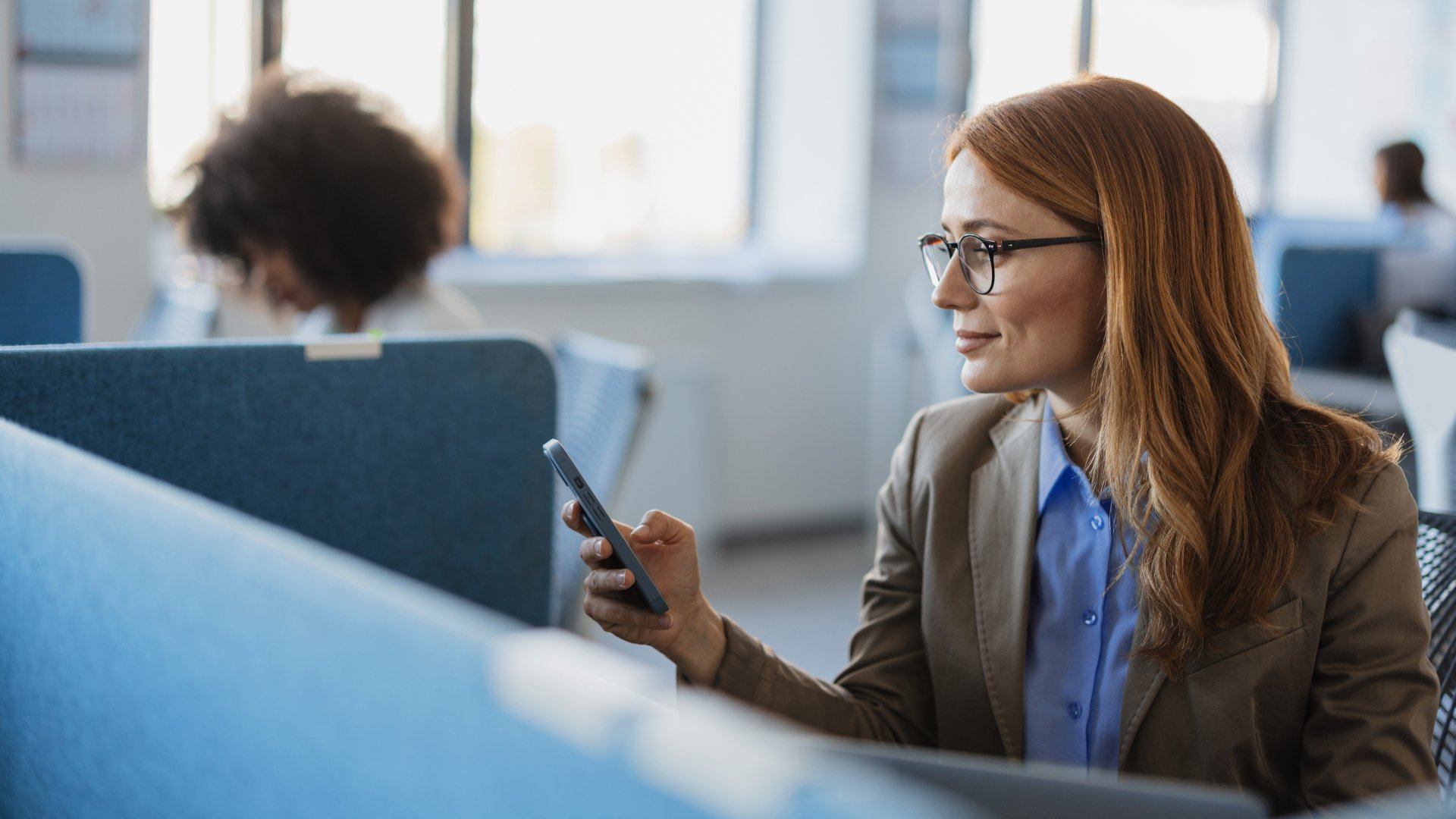 Eine Frau im Büro tippt etwas auf einem Smartphone ein
