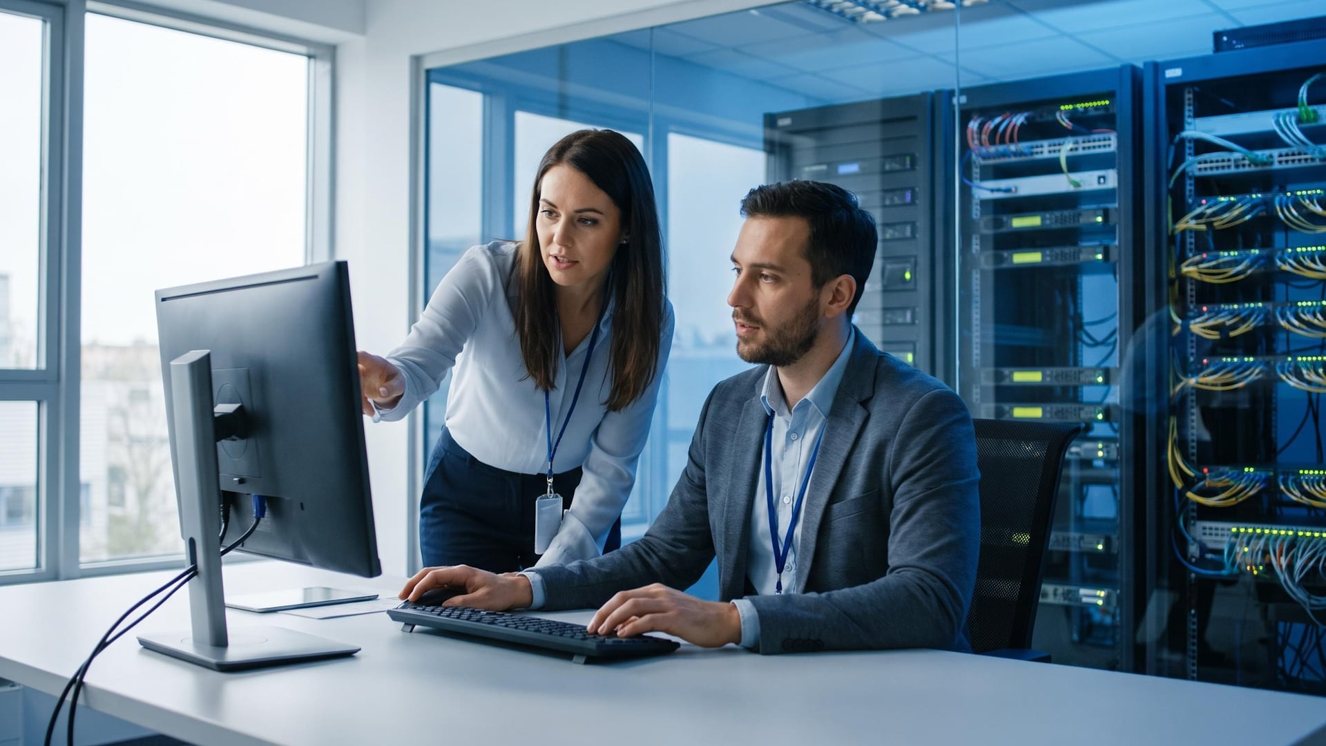 IT-Personal (männlich und weiblich) arbeitet in einem Büro an einem Desktop-Bildschirm