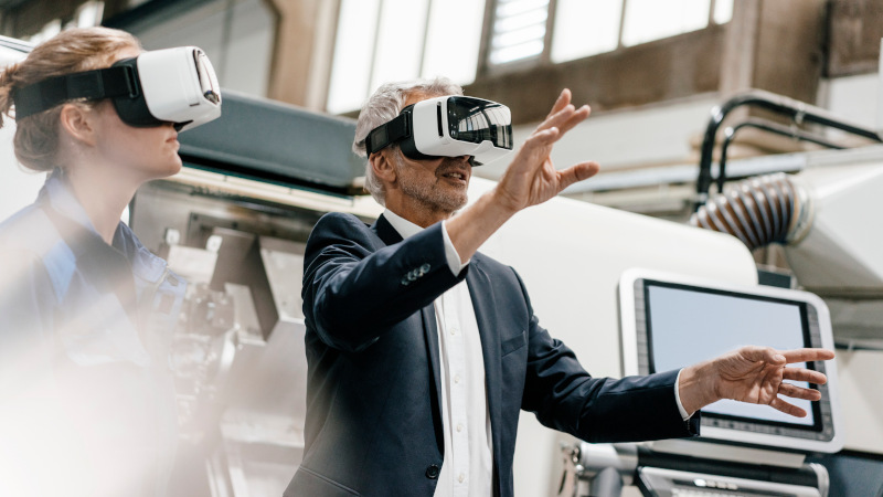 Eine Frau und ein Mann arbeiten mit VR-Brillen in einer vernetzten Fabrik 