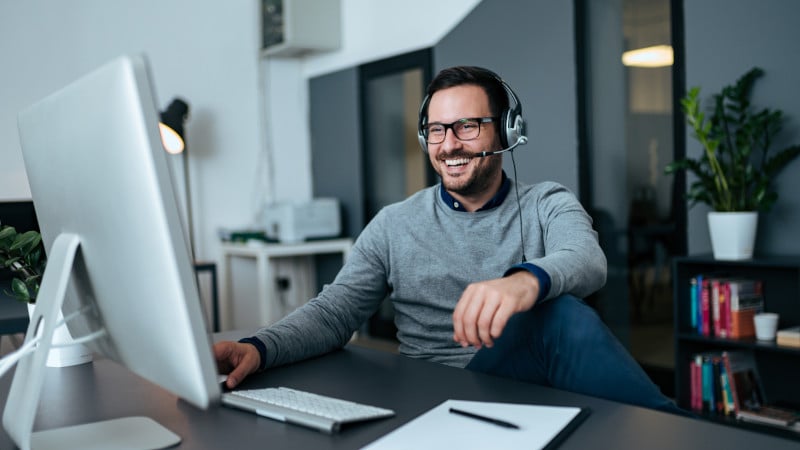 Ein junger Mann mit Headset telefoniert im Büro über Teams 