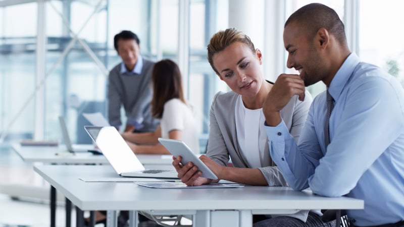 Teammitglieder mit Tablets und Laptops arbeiten und diskutieren in einem Büro