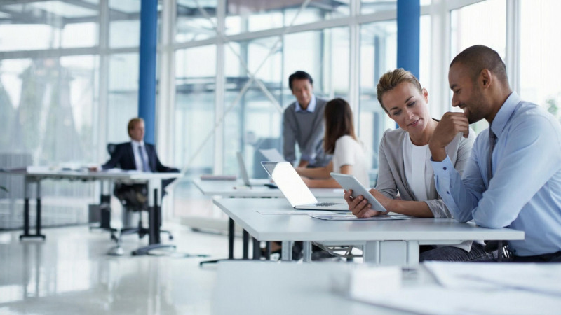 Teammitglieder mit Tablets und Laptops arbeiten und diskutieren in einem Büro