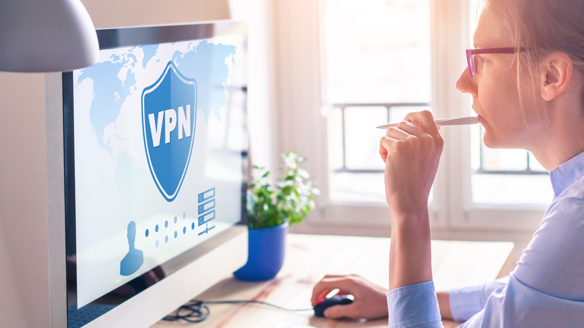 Eine Frau arbeitet am PC, auf dem Bildschirm ein VPN-Symbol