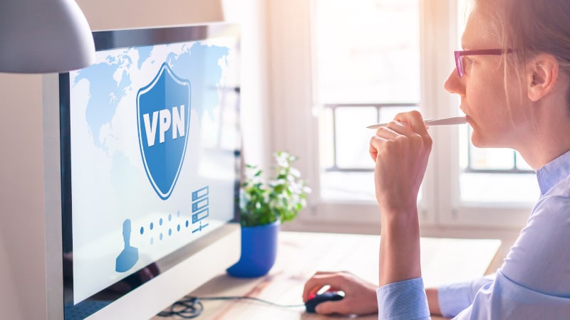 Eine Frau arbeitet am PC, auf dem Bildschirm ein VPN-Symbol