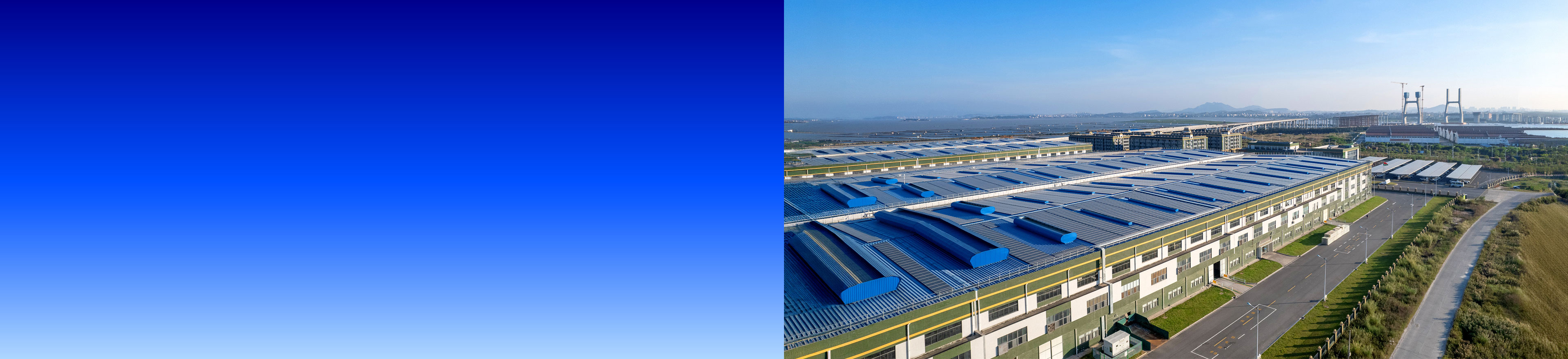 Luftaufnahme eines großflächigen Industriegeländes mit Fabrikhallen und Brücke im Hintergrund bei klarem Himmel, links blauer Farbverlauf.