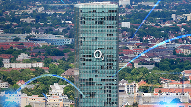 Hohes, grünes o2 Hochhaus vor einer Stadtlandschaft mit grafischen Netzwerk-Linien im Vordergrund.