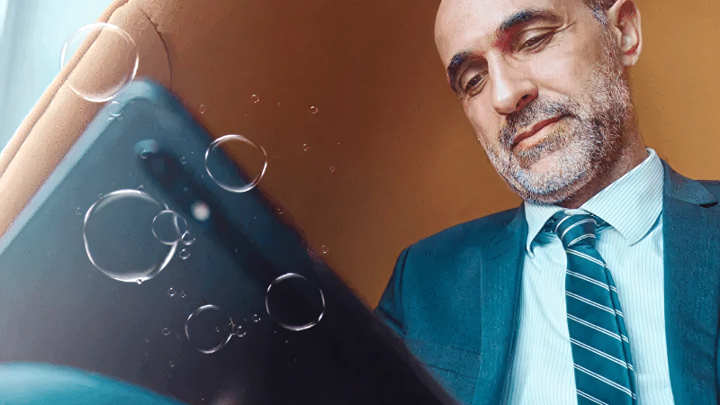 Abbildung: Smartphone mit Wassertropfen auf der Oberfläche, daneben eine Person in formeller Kleidung